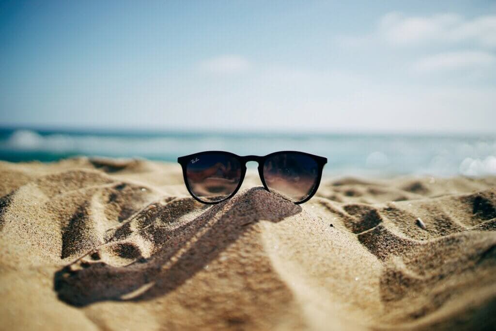 A pair of sunglasses on the sand on a beach