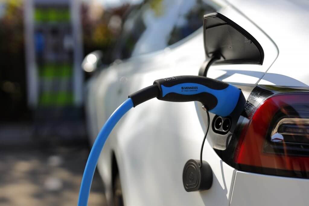 A blue charging cable charging a white car