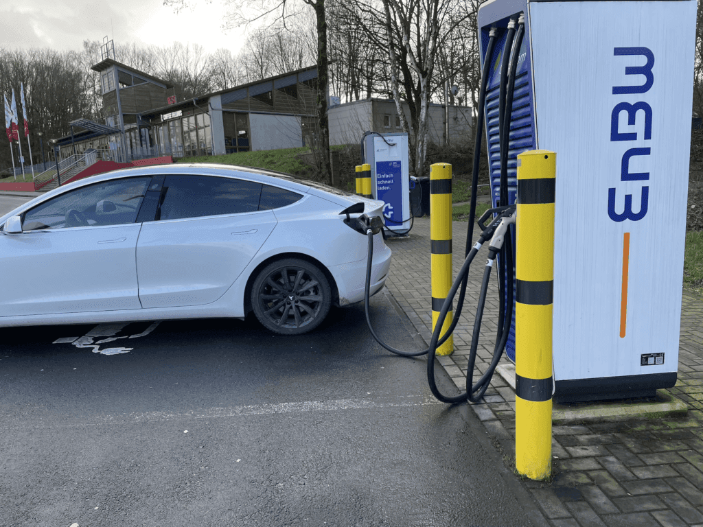 A white Tesla charging at a station in Germany